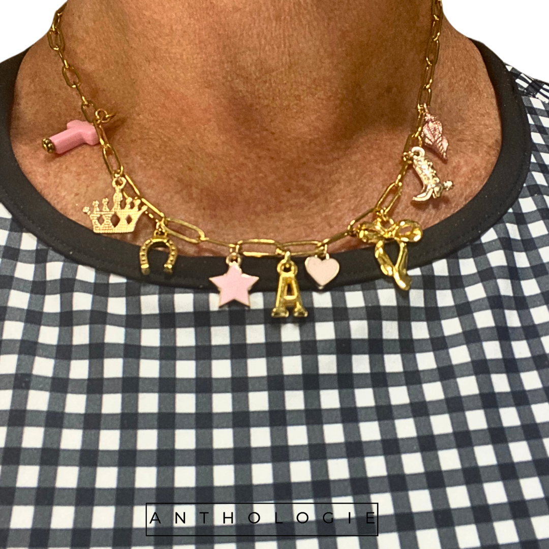 Necklace with various charms on a checkered fabric background, featuring the brand 'Anthologie'.